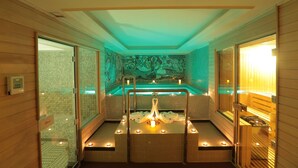 Un cuarto de spa con una bañera grande, puertas de cristal y piso de madera.