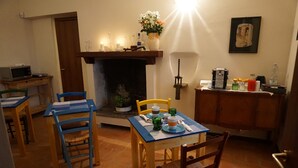 A cozy dining area with a fireplace, a coffee machine, and a dining table set for two. - La Casa Blu Bed & Breakfast (Calliano)