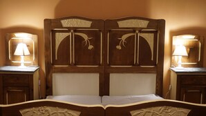 A double bed with a wooden headboard featuring floral carvings, flanked by two bedside tables with lamps. - La Casa Blu Bed & Breakfast (Calliano)
