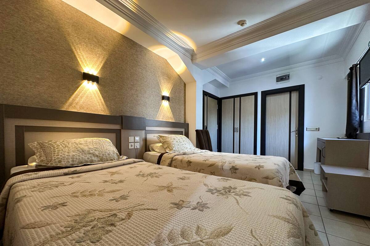 A hotel room with two beds, a desk, and a wardrobe.