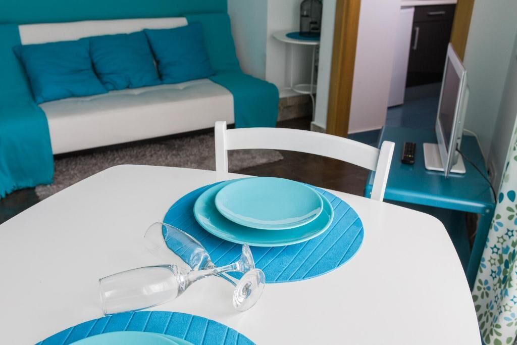 Une table à manger avec des sets de table et des assiettes bleues, un verre à vin et une chaise blanche.