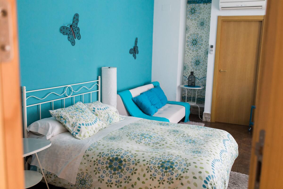 Une chambre à coucher avec un lit, une table de chevet, une petite table et une porte.