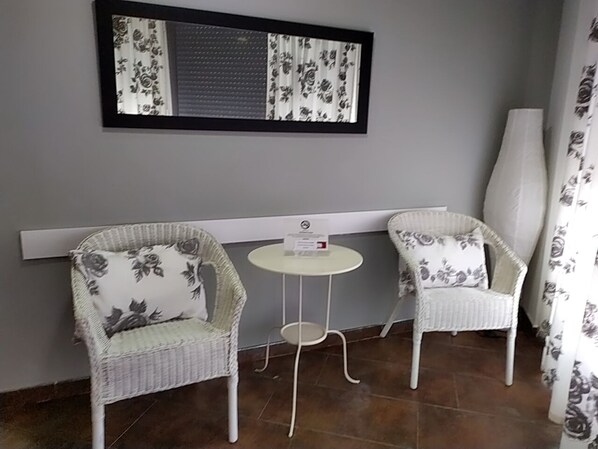A small room with two wicker chairs and a round table, a window with a floral blind, and a white wall. - Estudios Sierra de Francia  (Bejar)