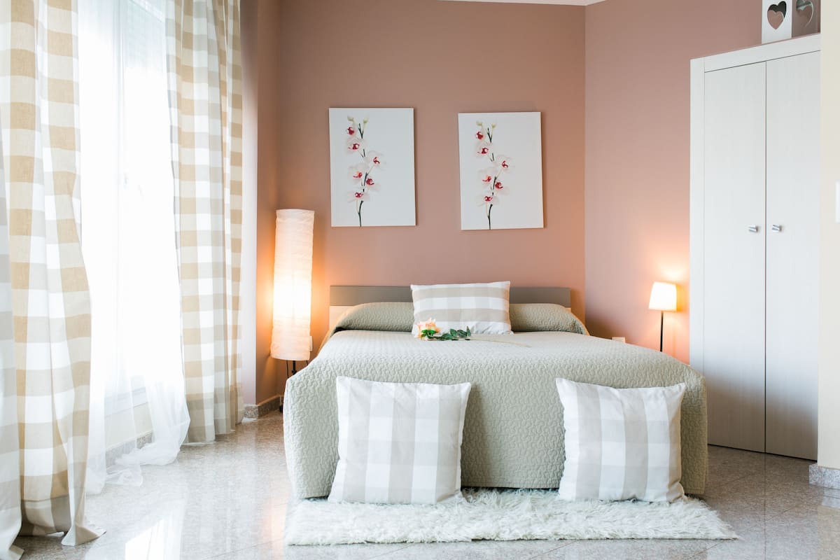 Une chambre bien rangée, avec un lit, deux lampes fixées au mur et une armoire.