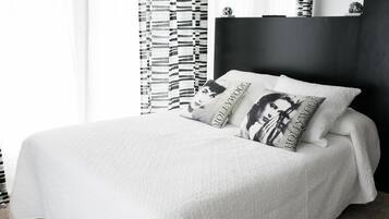Una cama bien hecha con ropa de cama y almohadas blancas que tienen el texto 'Hollywood'.
