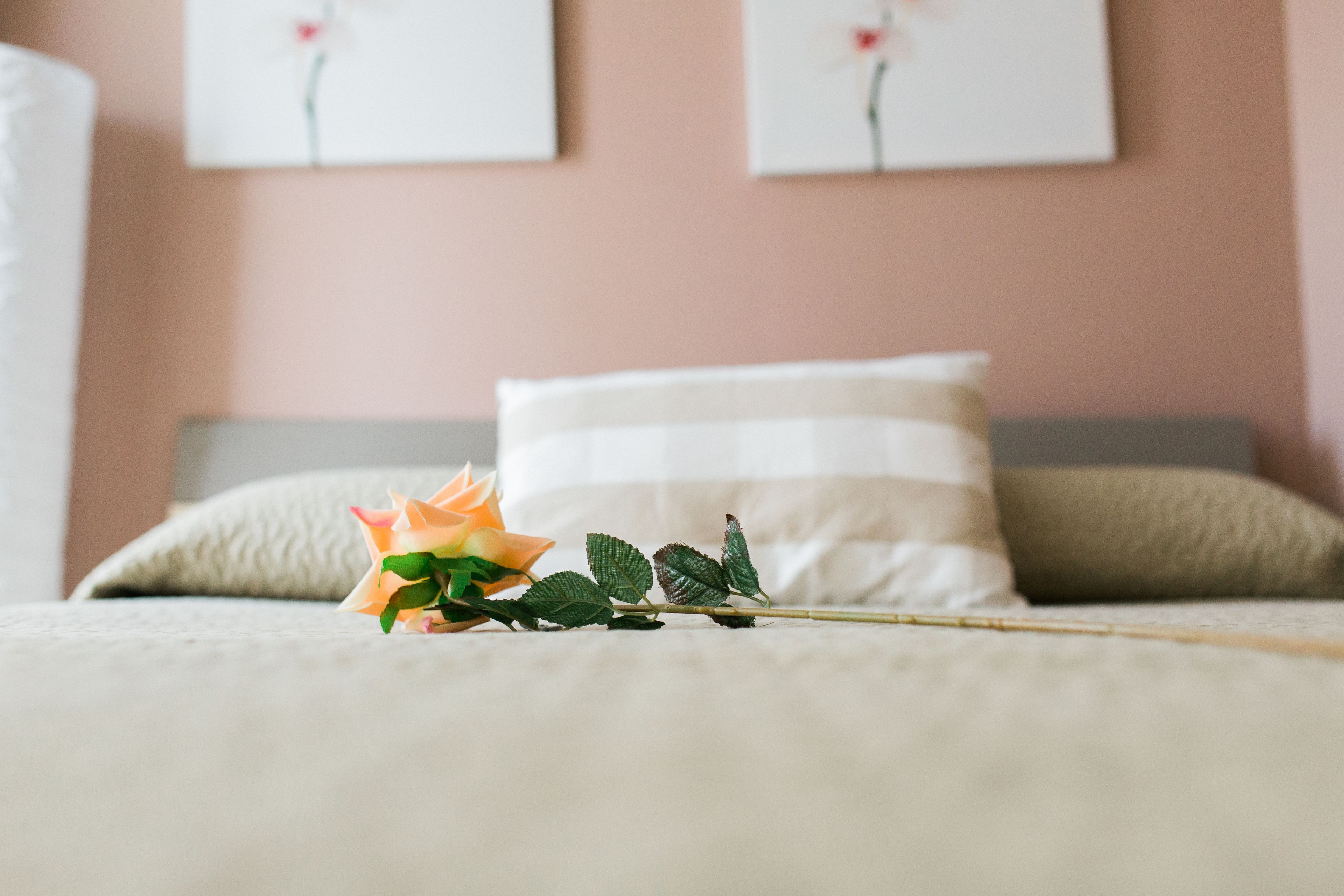 Ein Bett mit einer einzelnen Rose und einem Kopfkissen.