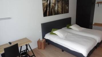 A bedroom with a bed, a desk, and a chair.