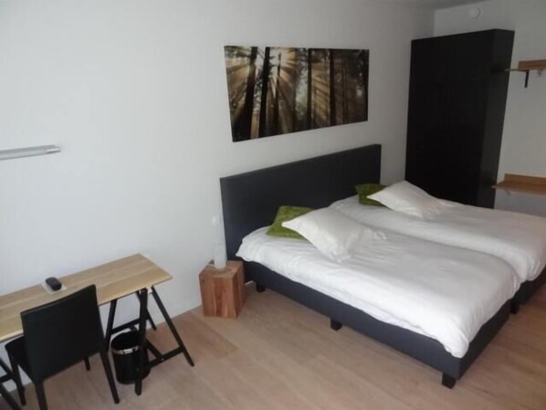 Un dormitorio con cama, escritorio y silla.