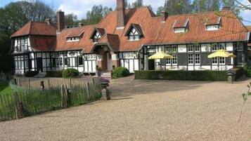 A traditional building with a gravel courtyard, multiple chimneys, and a large entrance.