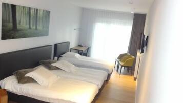 Une chambre d’hôtel moderne, dotée d’un grand lit, d’un bureau et d’une chaise.