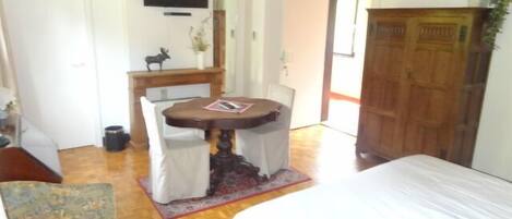 Una habitación con cama, una mesa de comedor con sillas, un televisor y una puerta de madera.
