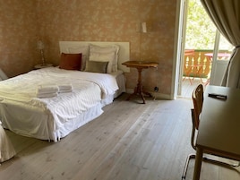 Habitación de hotel con cama, una mesita, una silla y vistas al exterior.