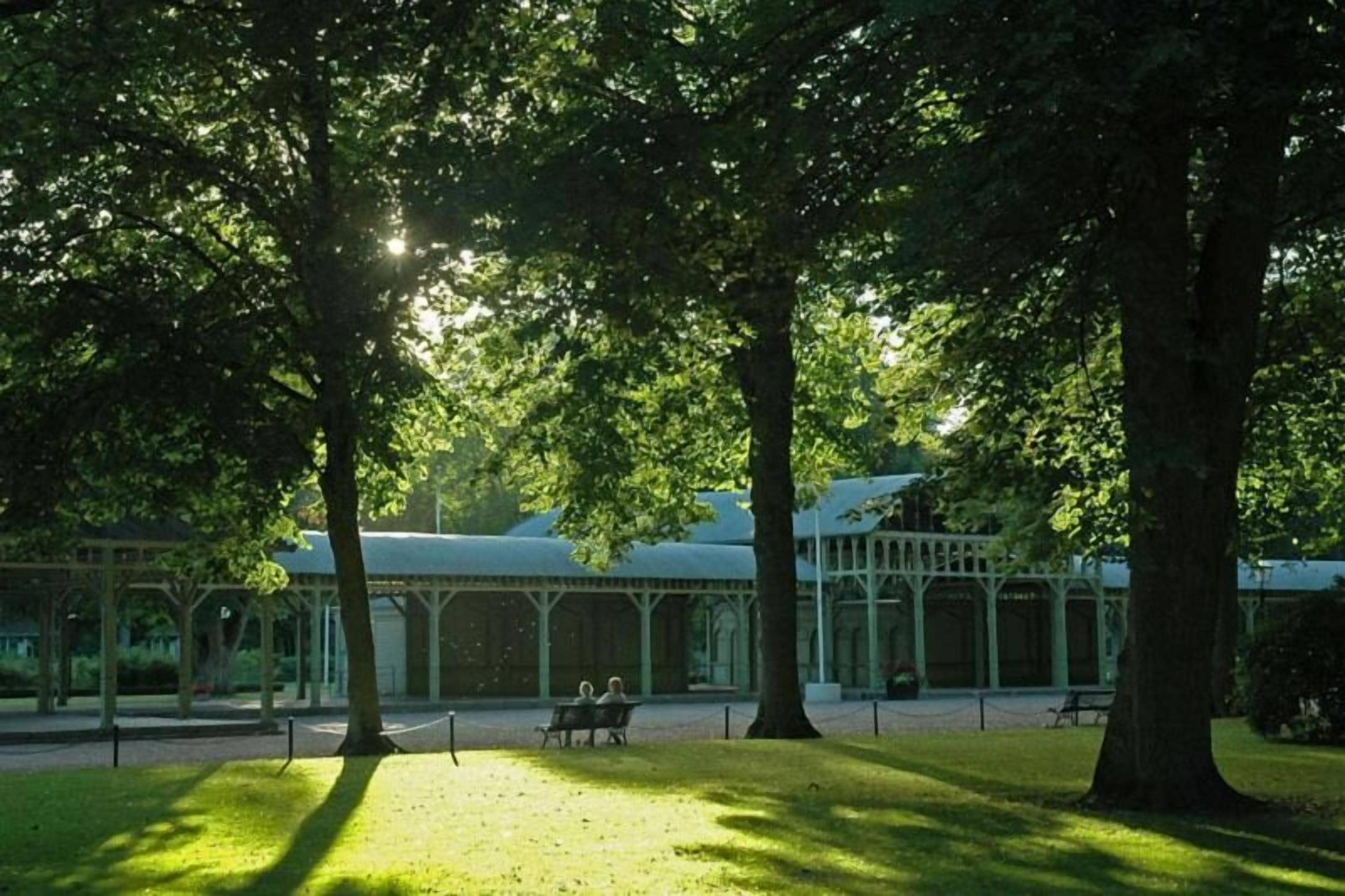 Un parque con árboles, un pabellón y un banco.