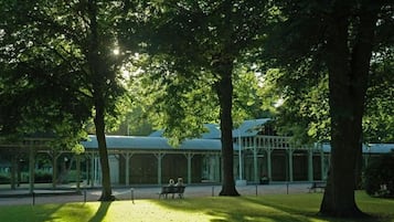 En park med træer, en lystpavillon og en bænk.
