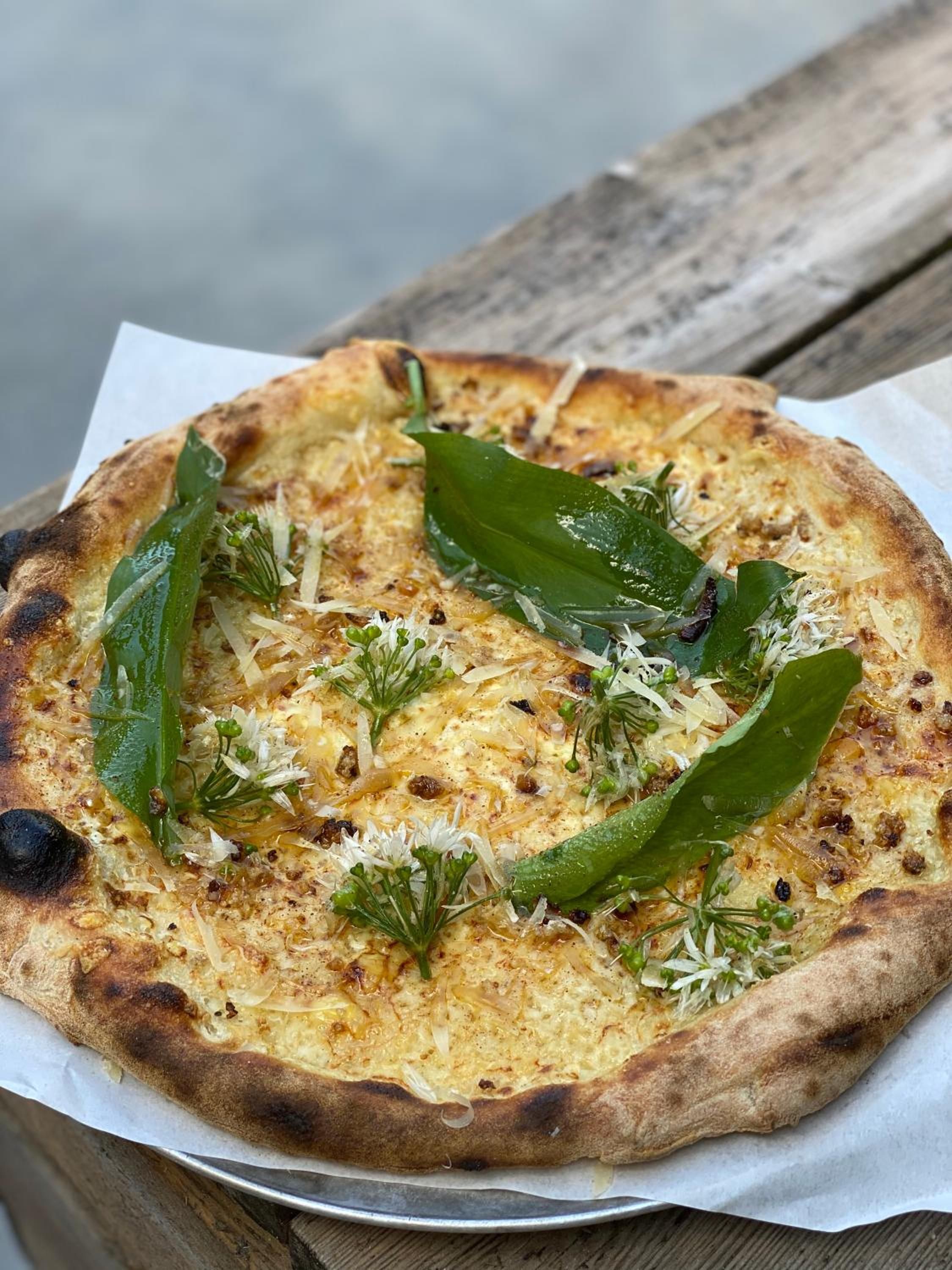 A pizza with toppings on a wooden surface.