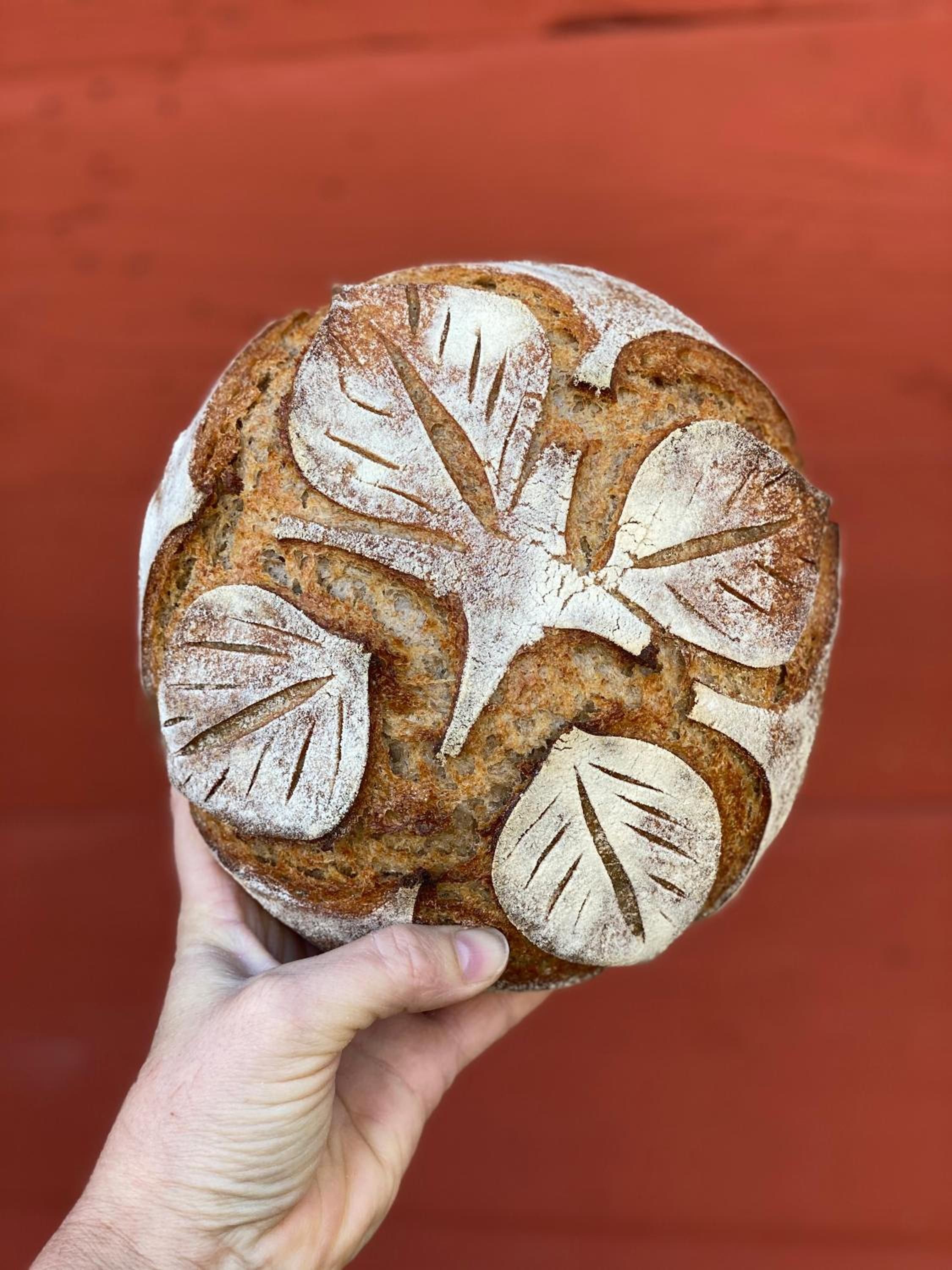 Una hogaza de pan con una mano sosteniéndola.