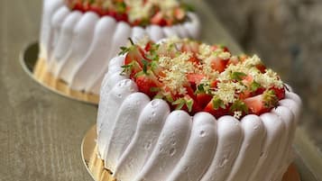 Three white frosted cakes with strawberries and green garnish on a wooden table.