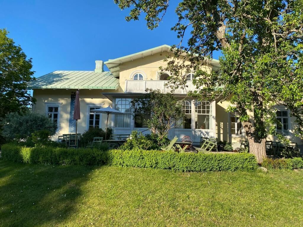 A two-story house with a balcony, a lawn, and a tree in the foreground.
