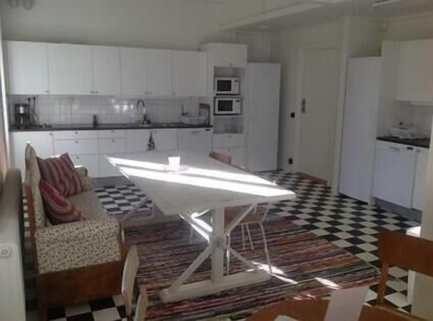 A compact kitchen with white cabinets, a microwave, and a checkered floor.