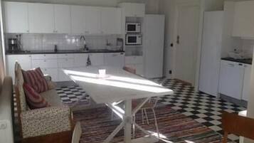 A compact kitchen with white cabinets, a microwave, and a checkered floor.