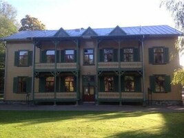 Un edificio de dos pisos con fachada simétrica, varias ventanas con contraventanas y una entrada central.