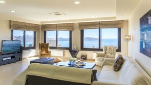 A spacious living room with a large flat-screen TV, comfortable seating, and a view of the sea. - Villa Panorama (Agios Nikolaos)