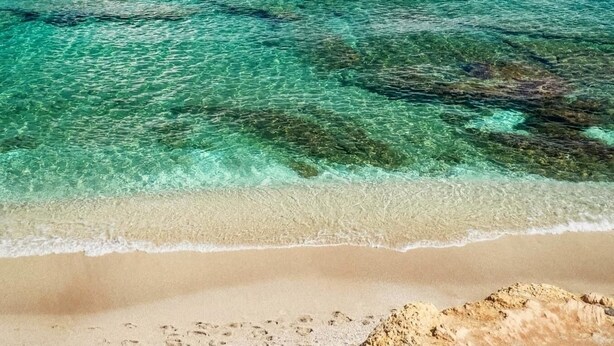 A beach with clear turquoise water, a sandy shore, and a clear sky with clouds. - Villa Panorama (Agios Nikolaos)