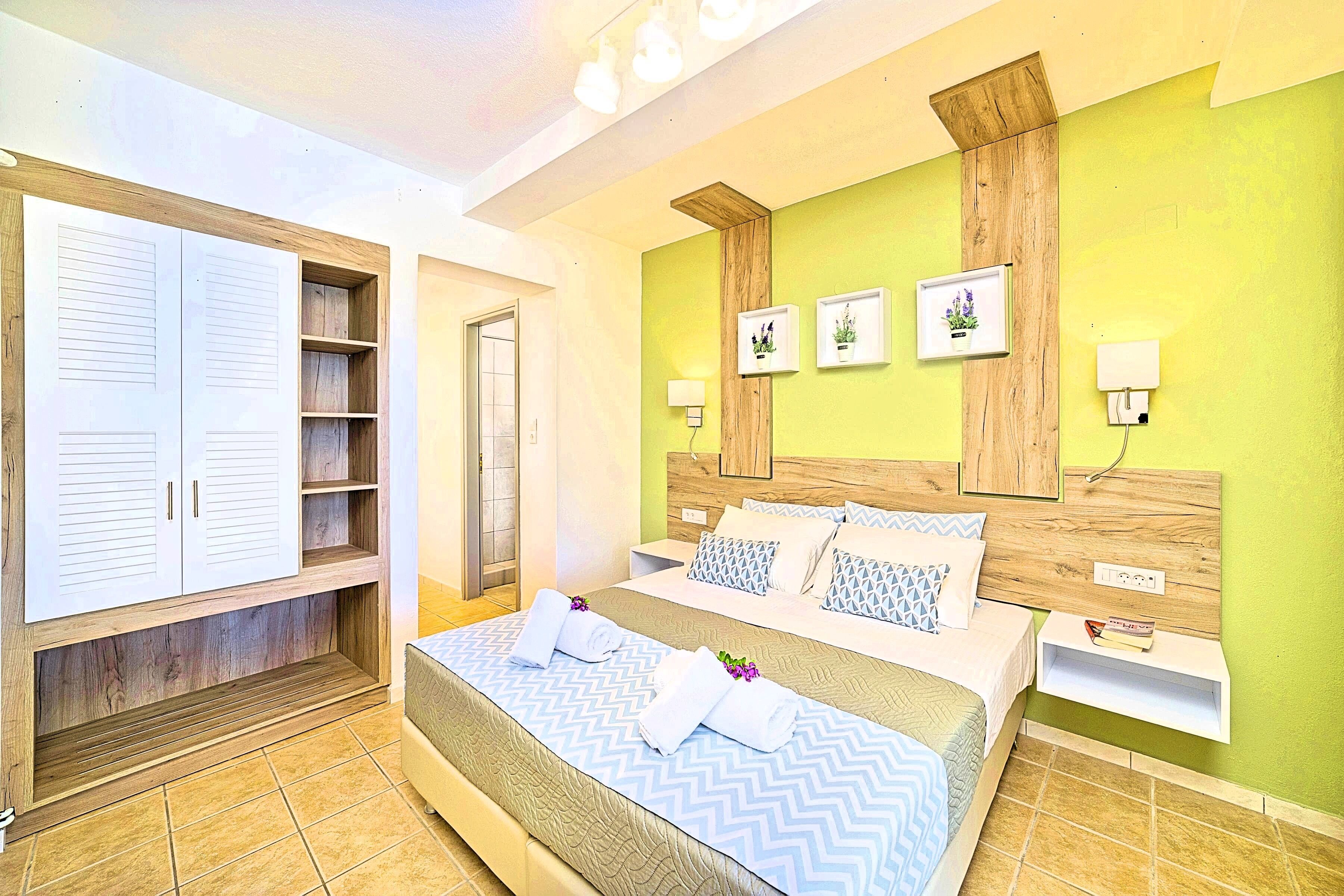 Une chambre à coucher comprenant un lit, une armoire, une table de chevet et une étagère fixée au mur.