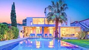 A modern two-story house with a swimming pool, outdoor seating, and a staircase leading to a stone roof. - Cretan Mansion with Heated Swimming Pool (Apokoronas)