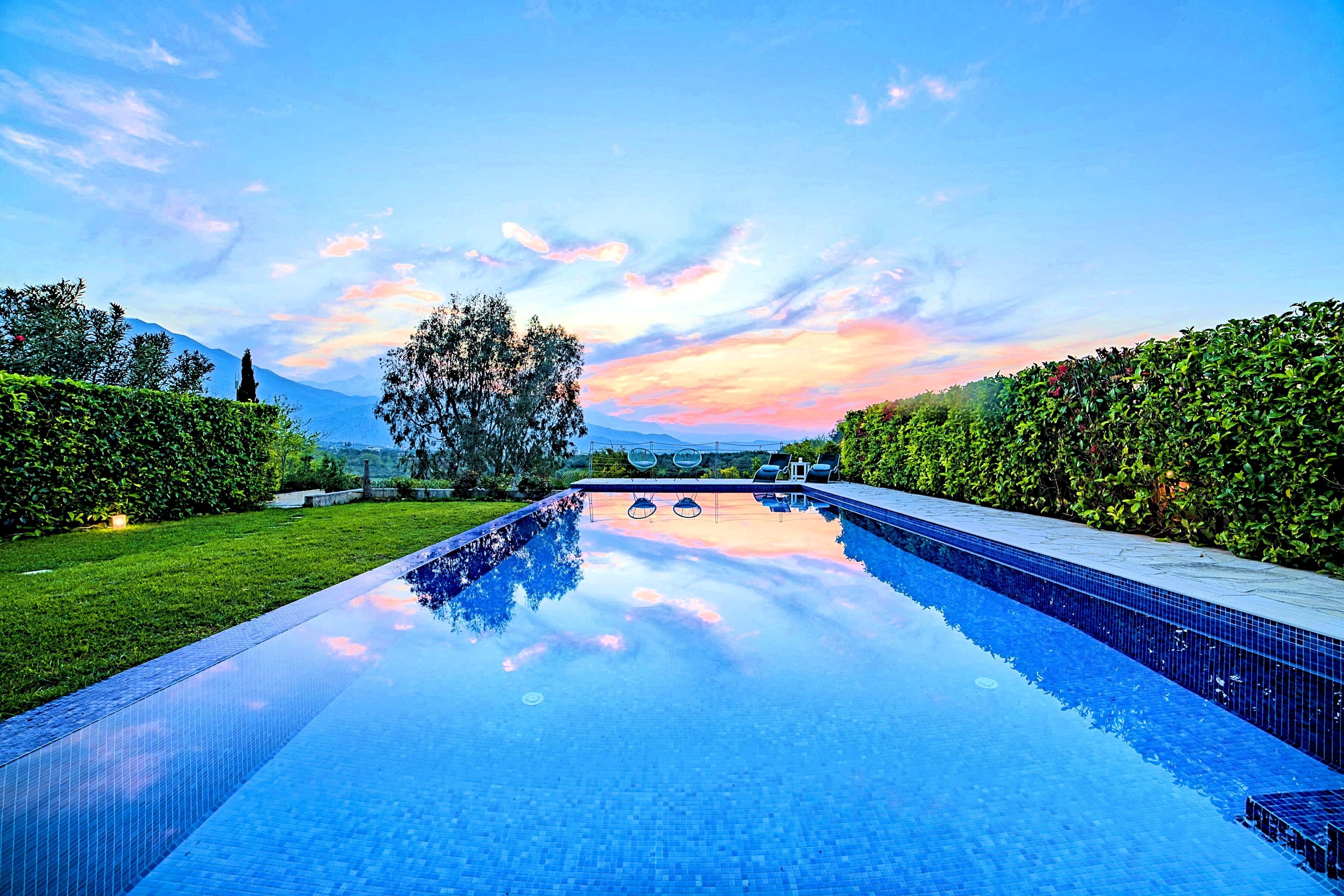 Una piscina sense fi rectangular amb vista clara al cel i muntanyes allunyades.