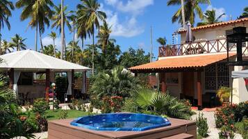 Relax in a serene outdoor oasis with a hot tub surrounded by lush greenery and palm trees.