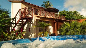 A building with a staircase leading to a covered area, surrounded by tropical vegetation. - 21 Palms (Las Galeras)