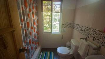 Un baño con bañera, inodoro y ventana.
