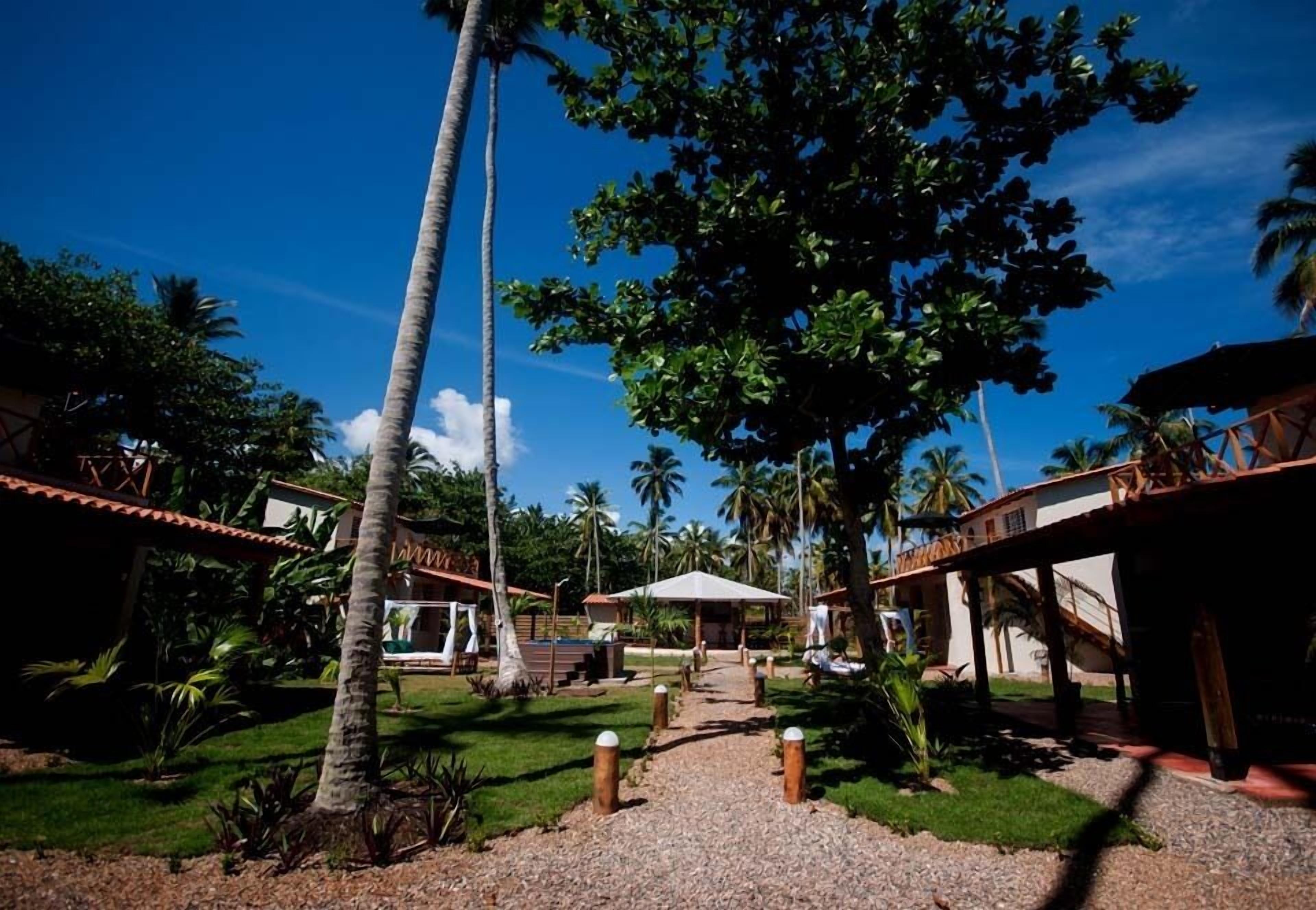 A tropical resort with palm trees, a covered walkway, and a building with a tiled roof.