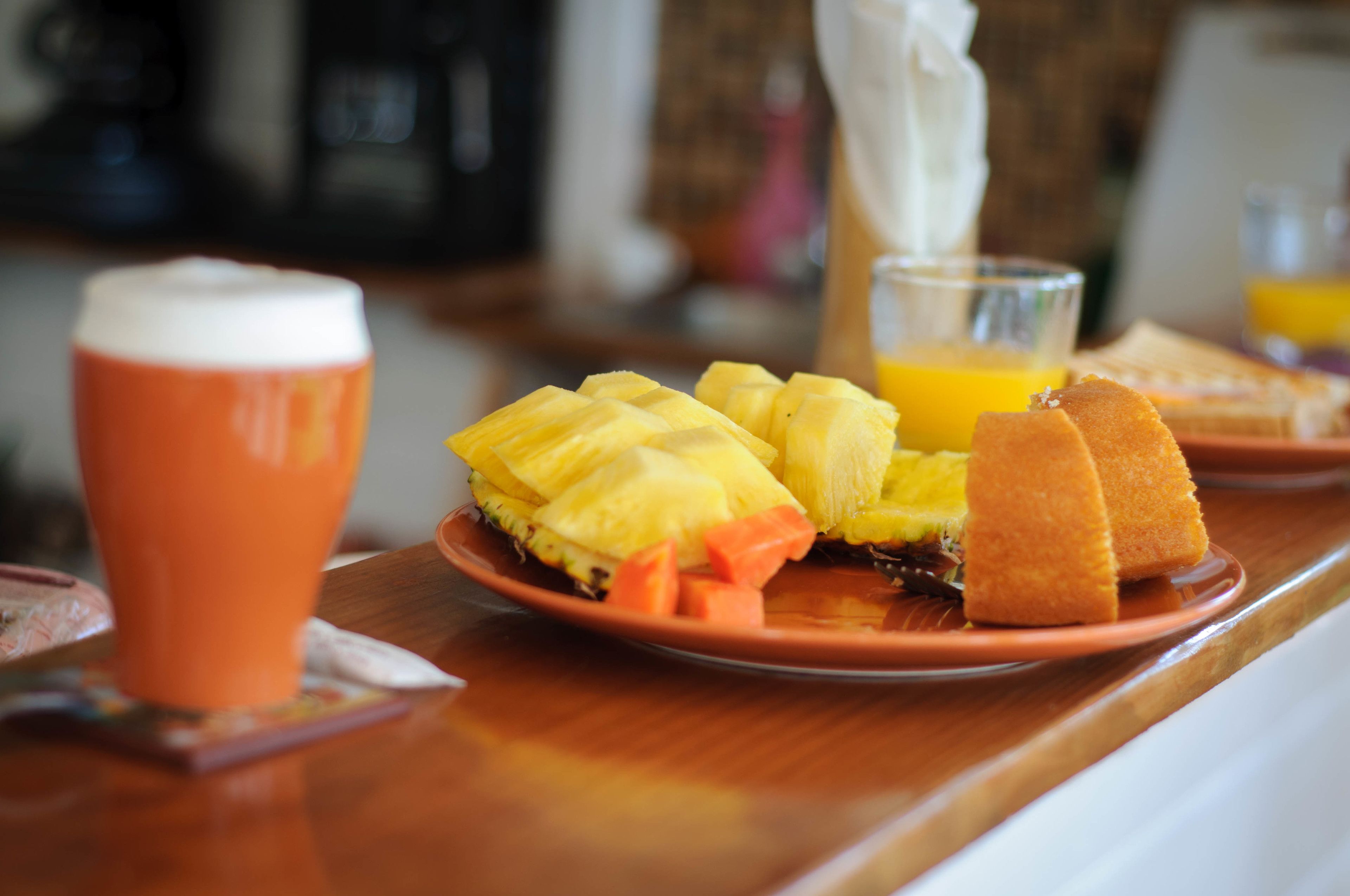 Una colazione servita su un tavolo di legno, con ananas, succo d'arancia e pane tostato.