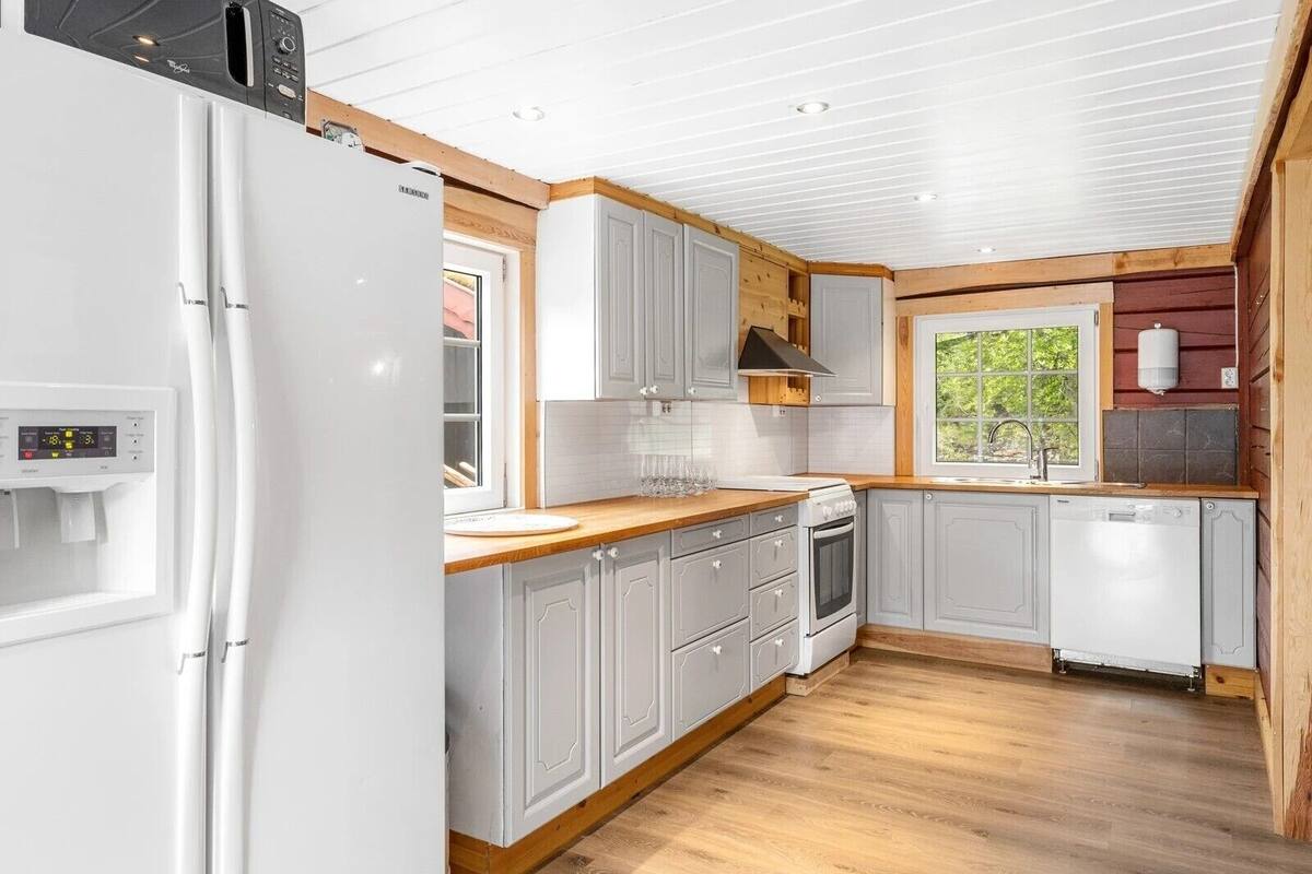 A compact kitchen with white cabinets, a built-in oven, and a dishwasher.