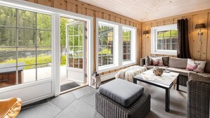 A cozy room with a large window, a sofa with decorative pillows, and a wicker ottoman.