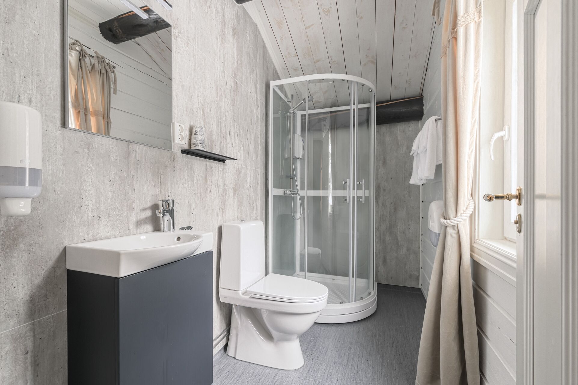 A modern bathroom with a glass-enclosed shower, a white sink, and a toilet.