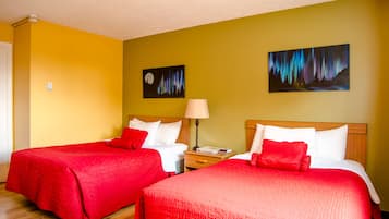 A hotel room with two beds, each with red bedding, a nightstand with a lamp, and two paintings on the walls.