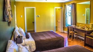 Una habitación con dos camas, un escritorio y una silla. Hay un espejo en la pared y una ventana con cortinas.