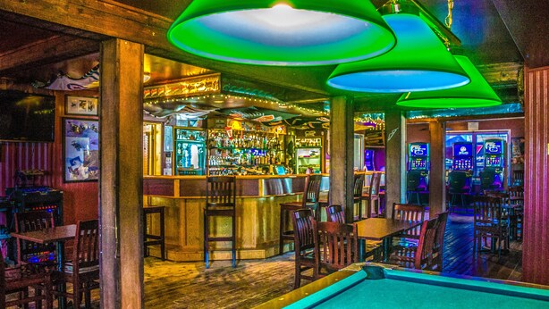 Un bar con mobiliario de madera y una mesa de billar.