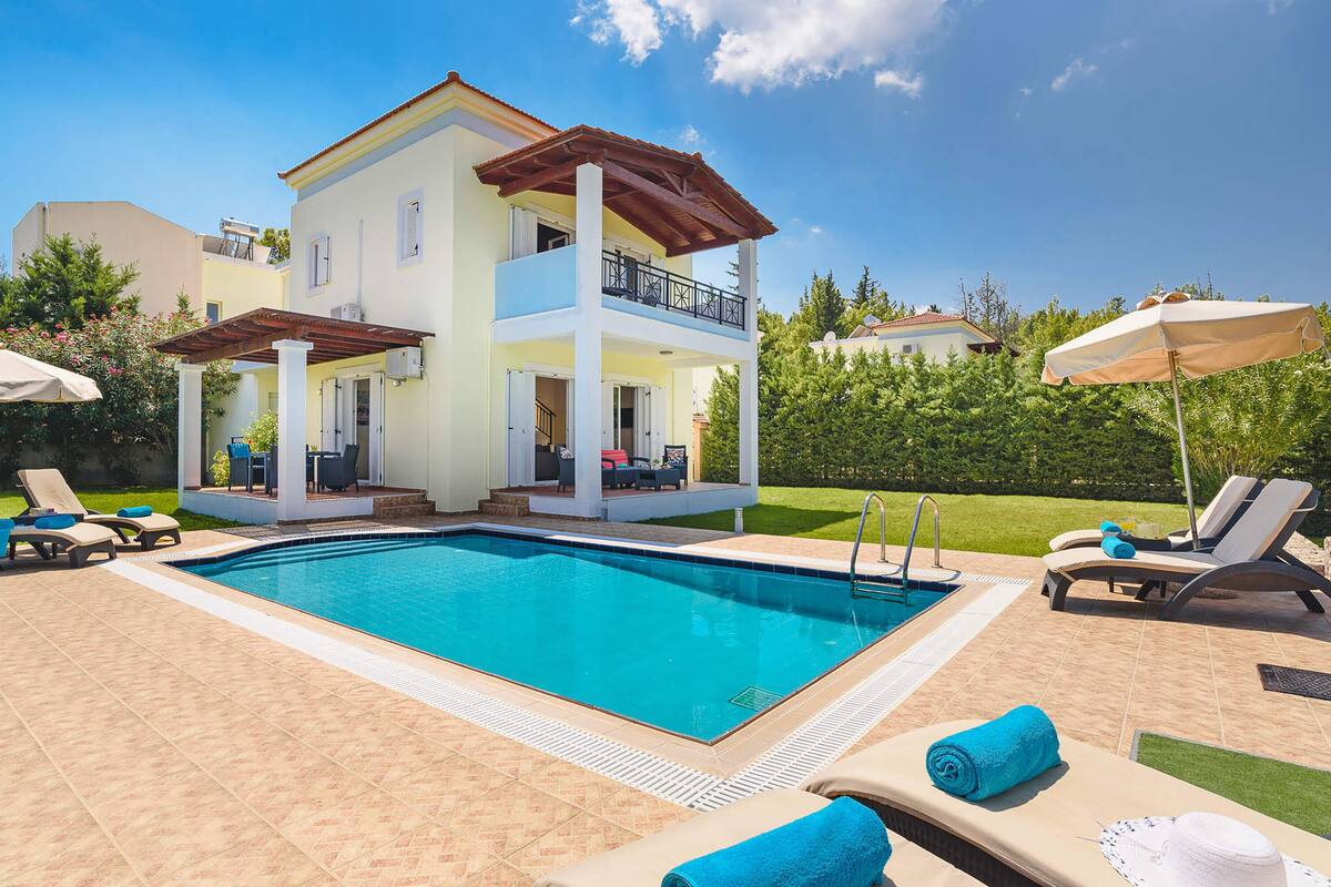 A two-story house with a swimming pool, outdoor seating, and a garden.