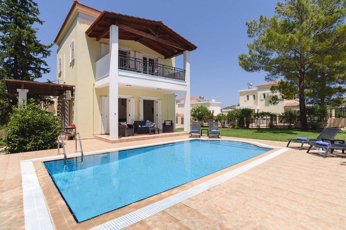 A two-story building with a swimming pool, outdoor seating, and a covered patio.