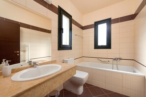 Un baño con lavamanos, inodoro y bañera.