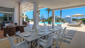 A dining area with a table set for six, overlooking a pool and palm trees. - Grande Dame Villa of Rhodes (Rhodes)
