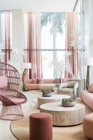 Una sala de estar moderna con un sofá rosa, una silla de mimbre y una mesa de centro redonda.