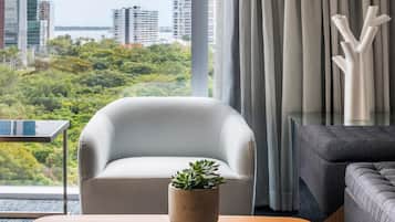 A modern living room with a view of a cityscape and greenery.