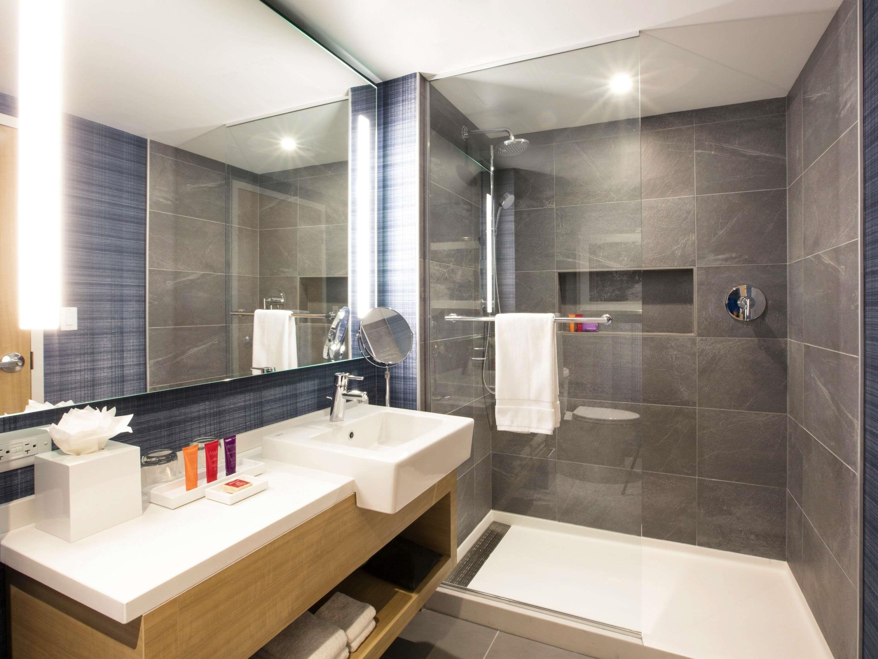 Un baño moderno con dos lavamanos, un espejo grande y una ducha a ras de suelo.
