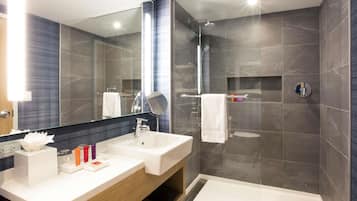 Un baño moderno con dos lavamanos, un espejo grande y una ducha a ras de suelo.