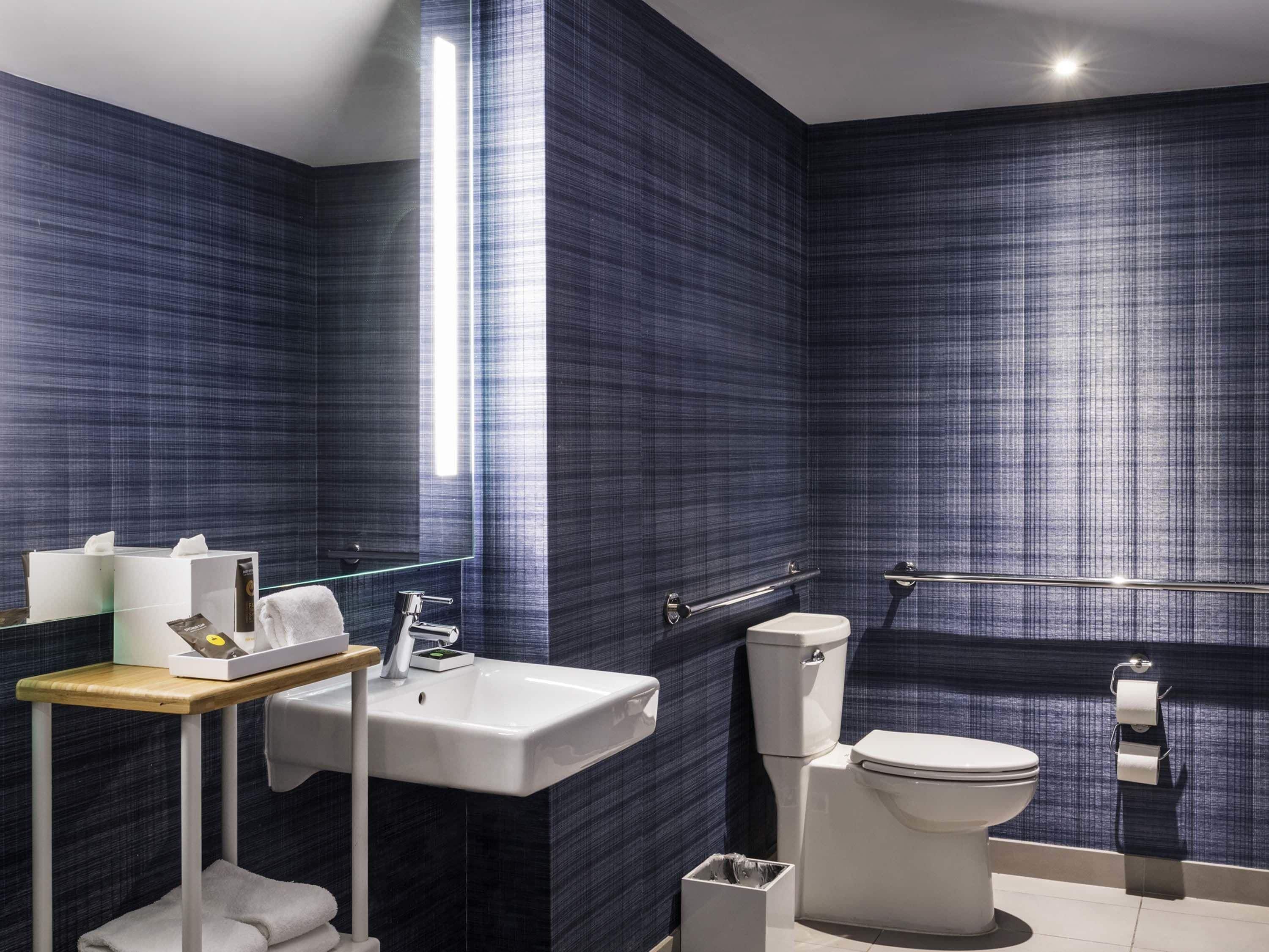 A modern bathroom with a white sink, toilet, and a glass shower enclosure.